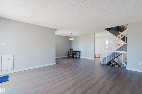 Spacious living area featuring light gray walls, textured white ceilings, and light wood-style flooring - 17308 61 Avenue, Edmonton, AB - Indoor