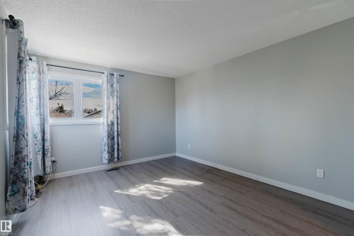 This room features light grey walls and wood-look flooring, creating a neutral and inviting atmosphere - 17308 61 Avenue, Edmonton, AB - Indoor Photo Showing Other Room