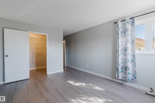 This room features grey wood-look flooring, light grey walls, and a window with a curtain rod and drapes - 17308 61 Avenue, Edmonton, AB - Indoor