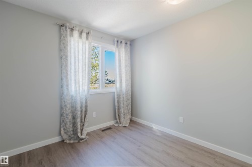 This room features light grey walls, light wood-look flooring, and a window with white trim - 17308 61 Avenue, Edmonton, AB - Indoor Photo Showing Other Room