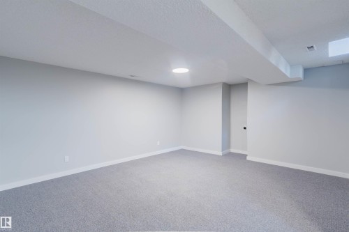 Spacious room featuring light grey carpet, white baseboards, and a circular ceiling light fixture - 17308 61 Avenue, Edmonton, AB - Indoor