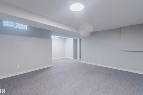The property offers a spacious room with light gray carpeting and light-colored walls, featuring a window and overhead lighting - 17308 61 Avenue, Edmonton, AB - Indoor