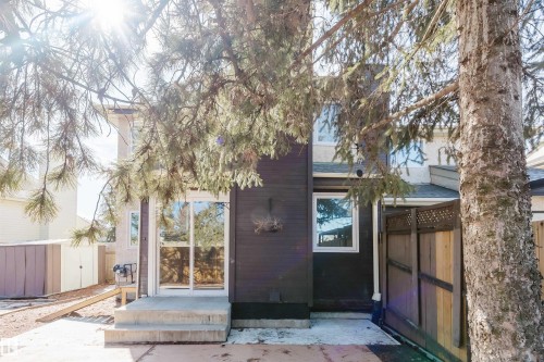 The exterior of the property features a dark-colored siding, a white-trimmed window, and a sliding glass door that opens onto a concrete patio - 17308 61 Avenue, Edmonton, AB - Outdoor
