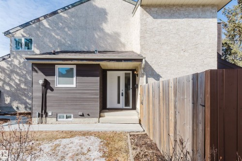 The property exterior features textured stucco and horizontal siding, with a white front door and surrounding windows - 17308 61 Avenue, Edmonton, AB - Outdoor