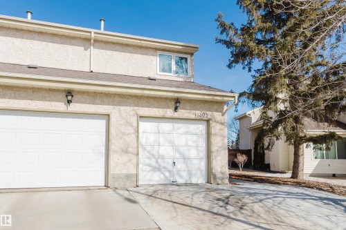 This property features a light-colored exterior, two garage doors, and a clear concrete driveway - 17308 61 Avenue, Edmonton, AB - Outdoor