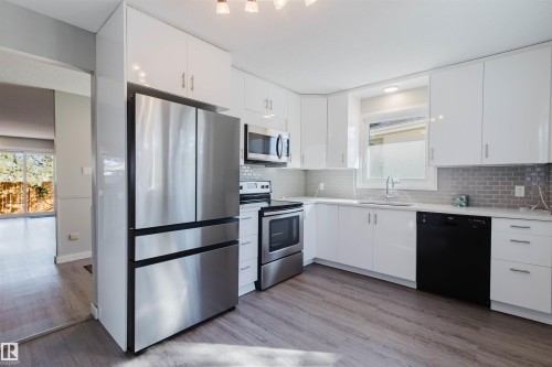 The kitchen features white cabinetry, stainless steel appliances, and sleek countertops - 17308 61 Avenue, Edmonton, AB - Indoor Photo Showing Kitchen With Stainless Steel Kitchen With Upgraded Kitchen