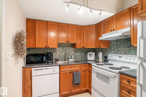 The kitchen features wooden cabinetry, a dark countertop, and a patterned backsplash - 5 4902B 43 Street, Legal, AB 