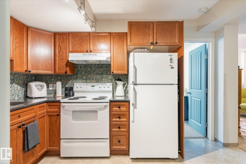 The kitchen features wood cabinetry, a white refrigerator, and a white electric range - 5 4902B 43 Street, Legal, AB 
