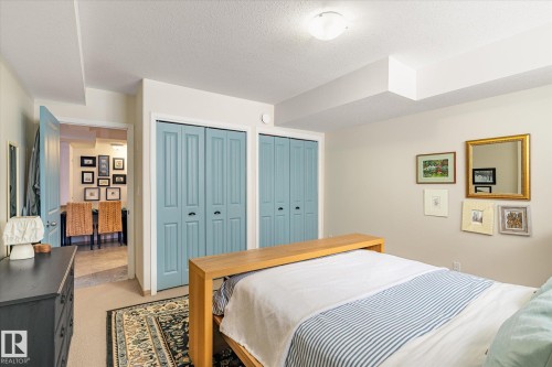 This room features neutral-toned walls, two sets of bi-fold closet doors, and a carpeted floor with an area rug - 5 4902B 43 Street, Legal, AB 