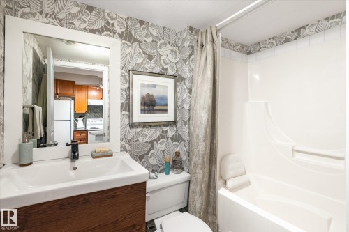 Bathroom featuring a white vanity with a rectangular sink, a toilet, and a combination shower and bathtub - 5 4902B 43 Street, Legal, AB 
