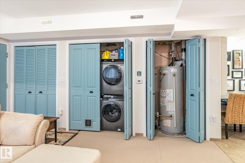 This property features light blue bi-fold doors, one set of which reveals a stacked washer and dryer unit - 5 4902B 43 Street, Legal, AB 