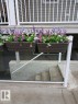 Exterior siding with white baluster railing and planter boxes featuring colorful flowering plants - 5 4902B 43 Street, Legal, AB 