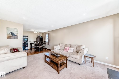 The property features an inviting living area with light-colored carpeting, leading into a dining area with hardwood flooring - 11323 162 Avenue, Edmonton, AB - Indoor Photo Showing Living Room