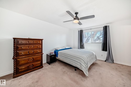 This room features a ceiling fan with integrated lighting, a window with curtains, and carpeting - 11323 162 Avenue, Edmonton, AB - Indoor Photo Showing Bedroom