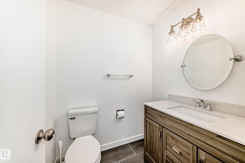 Bathroom featuring a vanity with a white countertop, an oval mirror, and a three-bulb light fixture - 11323 162 Avenue, Edmonton, AB - Indoor Photo Showing Bathroom