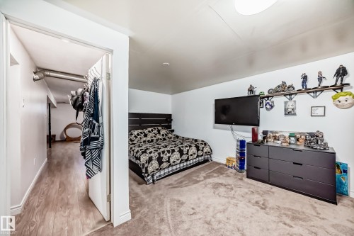A well-appointed room featuring a dark wood headboard, a dark grey dresser, and a wall-mounted television - 11323 162 Avenue, Edmonton, AB - Indoor Photo Showing Bedroom