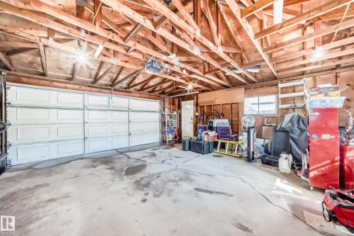 Spacious garage featuring a concrete floor, exposed wood beam ceiling, and a large white overhead door - 11323 162 Avenue, Edmonton, AB - Indoor Photo Showing Garage
