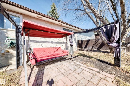 The property features a brick patio, a mature tree, and a fenced yard - 11323 162 Avenue, Edmonton, AB - Outdoor