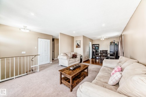 Inviting living area featuring light-colored carpeting, a rustic wood coffee table, and a dining area with hardwood flooring - 11323 162 Avenue, Edmonton, AB - Indoor Photo Showing Living Room