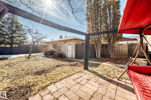 The property features a brick paver patio, a detached garage with a white door, and a fenced yard with mature trees - 11323 162 Avenue, Edmonton, AB - Outdoor