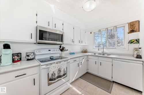 The kitchen features white cabinetry, white countertops, and a window above the sink - 11323 162 Avenue, Edmonton, AB - Indoor Photo Showing Kitchen With Double Sink