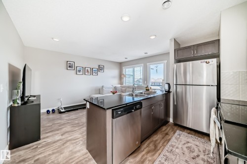 The open concept living area features resilient plank flooring and recessed lighting - 11 1530 Tamarack Boulevard, Edmonton, AB - Indoor Photo Showing Kitchen With Double Sink