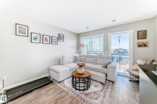 Living space featuring light-colored walls and wood-look flooring - 11 1530 Tamarack Boulevard, Edmonton, AB - Indoor Photo Showing Living Room