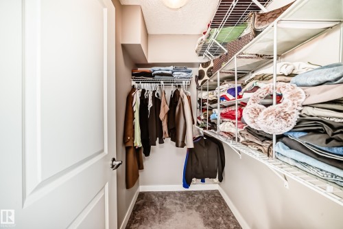 This walk-in closet features white wire shelving and hanging rods, providing ample storage space - 11 1530 Tamarack Boulevard, Edmonton, AB - Indoor With Storage