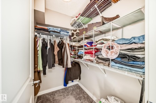 This property includes a closet featuring carpet flooring, white wire shelving, and hanging rods for clothing - 11 1530 Tamarack Boulevard, Edmonton, AB - Indoor With Storage