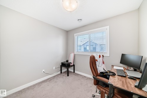 This room features a window with horizontal blinds, carpeted flooring, and a ceiling light fixture - 11 1530 Tamarack Boulevard, Edmonton, AB - Indoor Photo Showing Office