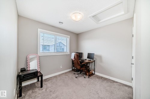 This room features a window with blinds, carpeted flooring, and a ceiling-mounted light fixture - 11 1530 Tamarack Boulevard, Edmonton, AB - Indoor Photo Showing Office
