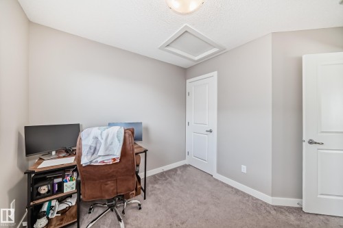 This room features neutral-toned walls, grey carpet, and white doors - 11 1530 Tamarack Boulevard, Edmonton, AB - Indoor
