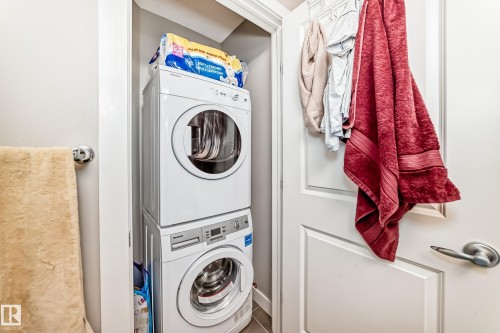 Dedicated laundry area featuring a white stackable washer and dryer - 11 1530 Tamarack Boulevard, Edmonton, AB - Indoor Photo Showing Laundry Room