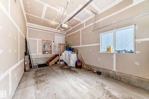 Spacious garage featuring a concrete floor, a window providing natural light, and a white door for access - 11 1530 Tamarack Boulevard, Edmonton, AB - Indoor Photo Showing Garage