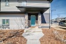 The property features an inviting entrance with a bright teal front door, complemented by stone-clad columns and a covered porch area - 11 1530 Tamarack Boulevard, Edmonton, AB  - Outdoor 