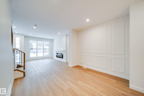 The property features hardwood floors, a fireplace, a large window, recessed lighting, and wall paneling - 9536 148 Street, Edmonton, AB - Indoor Photo Showing Other Room