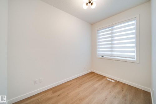 This room features light-toned wood flooring, a window with horizontal blinds, and a contemporary ceiling light fixture - 9536 148 Street, Edmonton, AB - Indoor Photo Showing Other Room