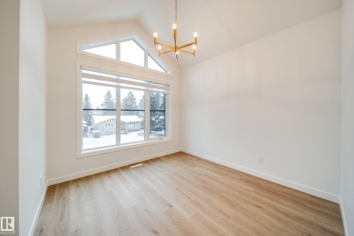 The property features light wood flooring, a vaulted ceiling, and an expansive window with a geometric upper pane - 9536 148 Street, Edmonton, AB - Indoor Photo Showing Other Room