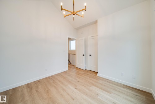 This bright room features a vaulted ceiling, light wood-style flooring, and a modern chandelier - 9536 148 Street, Edmonton, AB - Indoor Photo Showing Other Room