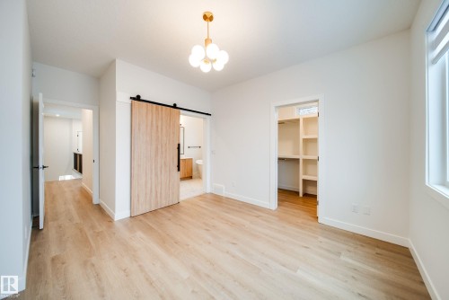Spacious room featuring light-toned flooring, a modern light fixture, and a window providing natural illumination - 9536 148 Street, Edmonton, AB - Indoor Photo Showing Other Room