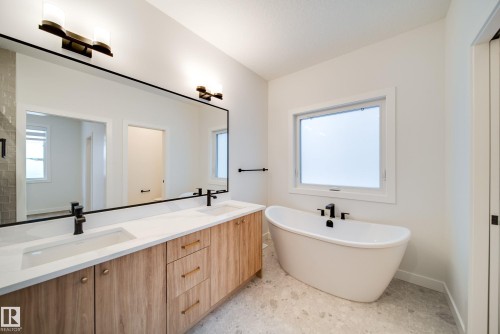 The bathroom features a large vanity with two sinks, light wood cabinetry, and a spacious mirror - 9536 148 Street, Edmonton, AB - Indoor Photo Showing Bathroom