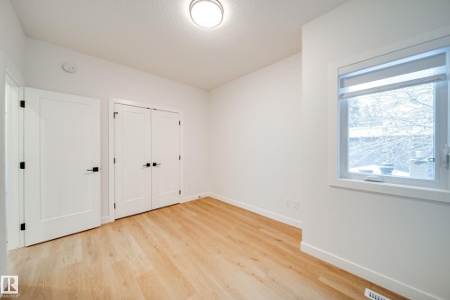 This room features light-toned wood flooring, white walls, and a window with a white frame - 9536 148 Street, Edmonton, AB - Indoor Photo Showing Other Room