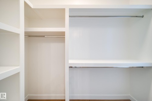 Built-in closet system featuring white shelving, hanging rods, and a light wood floor - 9536 148 Street, Edmonton, AB - Indoor With Storage