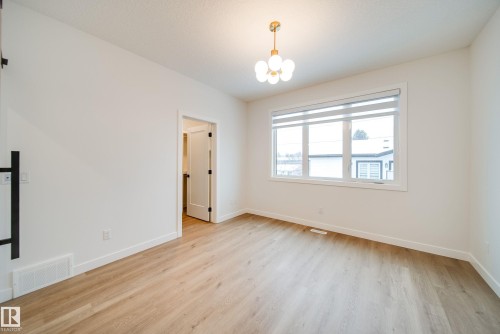 This room features light-colored flooring, a modern spherical chandelier, and a large window providing natural light - 9536 148 Street, Edmonton, AB - Indoor Photo Showing Other Room
