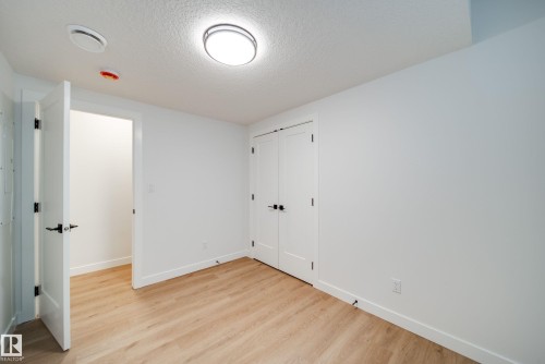 This room features light wood flooring, white walls, and a modern ceiling light fixture - 9536 148 Street, Edmonton, AB - Indoor Photo Showing Other Room