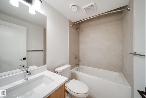 The bathroom features a vanity with a white countertop and rectangular sink, a toilet, and a bathtub with tiled walls - 9536 148 Street, Edmonton, AB - Indoor Photo Showing Bathroom