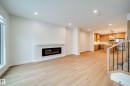 The living area features light wood flooring, an electric fireplace with a white mantel, and recessed lighting - 9536 148 Street, Edmonton, AB  - Indoor Photo Showing Living Room With Fireplace 