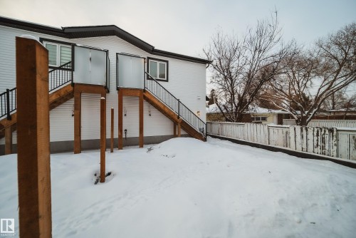 The property features white siding, a dark roof, and two exterior staircases with black railings - 9536 148 Street, Edmonton, AB - Outdoor With Exterior