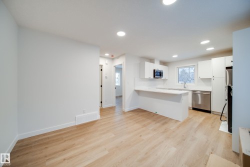Well-lit kitchen area with recessed lighting, light-toned flooring, white cabinetry, a stainless steel sink, and stainless steel appliances - 9536 148 Street, Edmonton, AB - Indoor Photo Showing Kitchen
