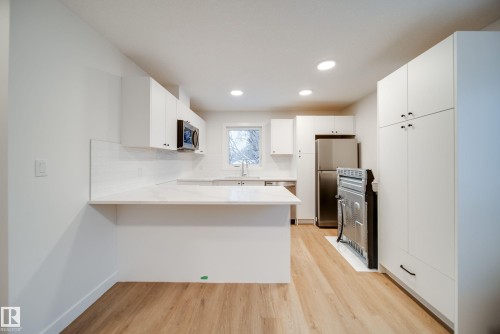 The kitchen features white cabinetry, light countertops, and a subway tile backsplash - 9536 148 Street, Edmonton, AB - Indoor Photo Showing Kitchen With Double Sink